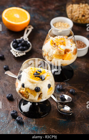 Maison saine layered dessert trifle à l'orange, myrtille, biscuit, yaourt et granola dans un verres Banque D'Images