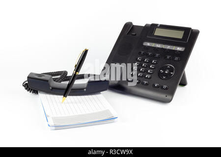 IP noir -téléphone, ordinateur portable et stylo pour écrire sur un fond blanc. Concept de poste de travail Banque D'Images