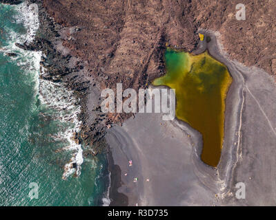 Vue aérienne du petit lac sous la montagne Bermeja, vue de la plage noire et la route côtière. Lanzarote, îles Canaries, Espagne Banque D'Images