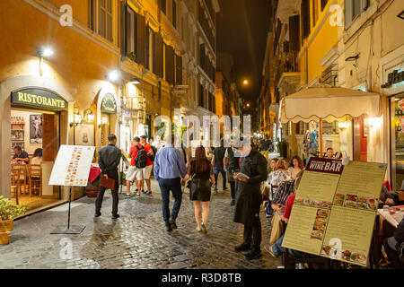 Scène nocturne à Rome comme les gens marchent le long de la rue pavée à la recherche d'un restaurant ou d'un café pour le dîner, Rome, Italie, Europe Banque D'Images