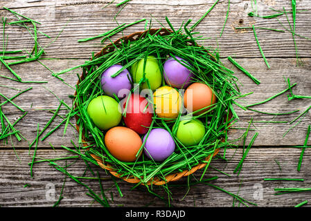 Oeufs de Pâques au printemps, l'arrière-plan avec les oeufs colorés dans leur nid sur table en bois Banque D'Images