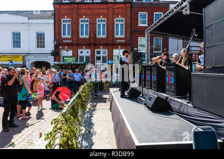 Faversham Hop Festival. Invicta Jazz Orchestra sur scène. Saxophoniste mâle debout sur le bord de la scène, orchestre en face de lui, derrière l'auditoire. Banque D'Images