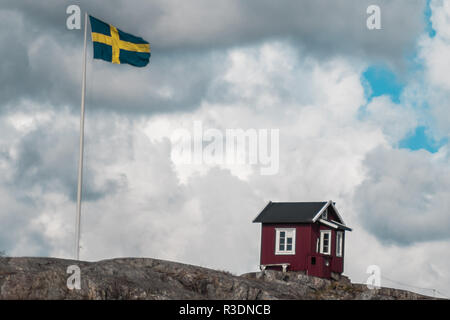 Une hutte rouge classique à côté d'un drapeau suédois sur Vrångö, dans l'archipel sud de Göteborg, en Suède Banque D'Images