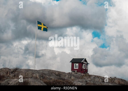 Une hutte rouge classique à côté d'un drapeau suédois sur Vrångö, dans l'archipel sud de Göteborg, en Suède Banque D'Images