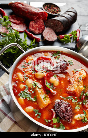 Close-up of Fabada Asturiana copieux Bean Stew. Principaux ingrédients - tranches de chorizo, boudins de poivre et le persil sur une planche à découper, espagnol c Banque D'Images