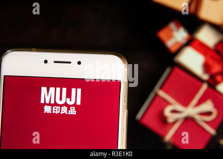 Conception de vêtements japonais et de détail de l'entreprise fabricant de mobilier Muji logo est vu sur un appareil mobile Android avec un cadeaux de Noël dans l'arrière-plan. Banque D'Images