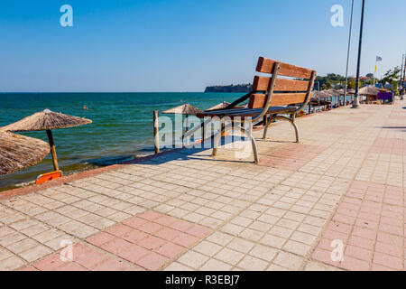 Banc en bois est placé sur l'allée carrelée derrière, mais au-dessus de la plage publique avec transats près de la côte. Banque D'Images