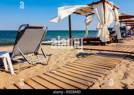 Chemin de bois va, grâce à une plage de sable, à la pergola en bois confortables avec rideau blanc sunny beach. Banque D'Images