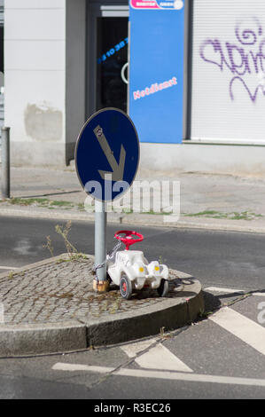 Une automobile en plastique blanc enchaîné à un poteau indicateur sur la rue à Berlin, en Allemagne, des graffitis sur les murs à l'arrière-plan Banque D'Images