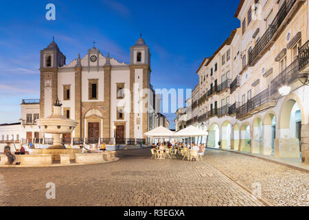 Praca do Giraldo et l'Igreja de Santo Antao avec les bâtiments historiques et les cafés autour de la place dans la soirée, Evora (Alentejo, Portugal, Europe Banque D'Images