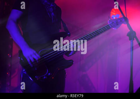 Guitare basse électrique player sur une scène en violet, l'éclairage d'arrière-plan photo avec effet de flou de mouvement Banque D'Images