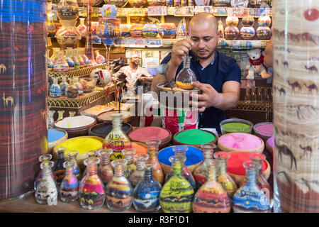 Dubaï, Émirats arabes unis - 12 novembre 2018 : Boutique de souvenirs à l'Atlantis Hôtel avec artisan faisant de souvenirs des bouteilles remplies de sable de couleur en forme de chameau Banque D'Images