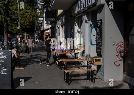 Les gens à l'extérieur de détente au soleil à la terrasse d'un café à Neukolln, Berlin, Allemagne. Banque D'Images