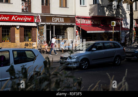 Les gens à l'extérieur de détente au soleil à la terrasse d'un café à Neukolln, Berlin, Allemagne. Banque D'Images