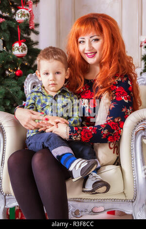 Heureuse mère et son petit enfant entouré de décorations de Noël Banque D'Images