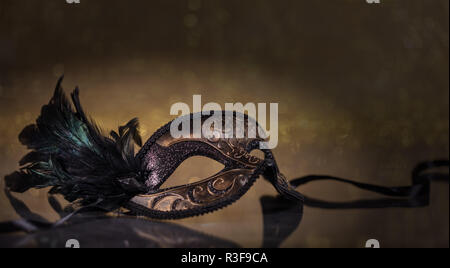 Le carnaval. Masque de Venise avec des plumes sur fond d'Or foncé, reflets, copy space Banque D'Images