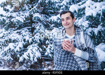 Jeune femme est titulaire d'tasse de café avec de la guimauve dans la forêt d'hiver Banque D'Images