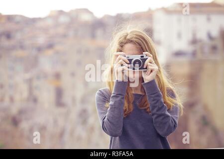 Fille avec appareil photo rétro parlant à l'extérieur, l'Italie, Pitigliano. Toscane Banque D'Images