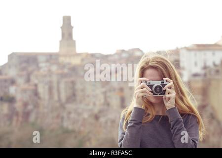 Fille avec appareil photo rétro parlant à l'extérieur, l'Italie, Pitigliano. Toscane Banque D'Images