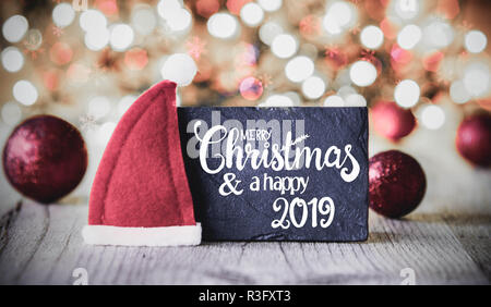 La plaque avec la calligraphie anglaise Joyeux Noël et une Bonne 2019. Et mousseux lumières fond étincelant. Décoration de Noël Boules violet comme un Banque D'Images