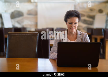 Belle mature Businesswoman Using Laptop au Coffee Shop Banque D'Images