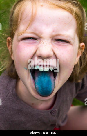Fillette de huit ans le repas / lécher une sucette / blue ice lolly pop qui est sa langue et des dents de coloration bleu. uk (98) Banque D'Images