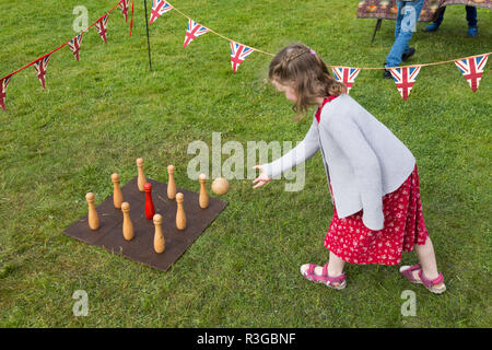 Une fillette de six ans jouant avec un vieux classique traditionnel jeu de quilles sur un conseil nécessitant le lancement d'une balle par les joueurs. Royaume-uni (98) Banque D'Images
