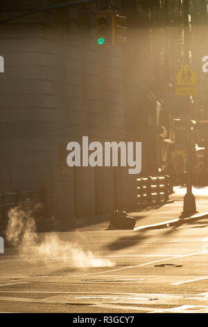 Beau lever de soleil dans les rues de Manhattan, avec un trou qui propulse la vapeur, New York, United States. Banque D'Images