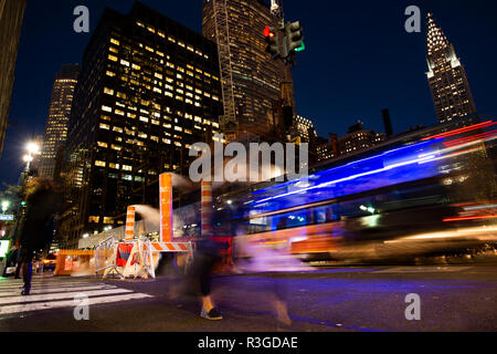 Une longue exposition photo de bus et les personnes qui traversent une intersection à New York pendant que la vapeur qui sort du trou. Manhattan, New York, United Banque D'Images