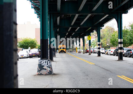 Un autobus scolaire est passé sous le pont de chemin de fer dans le Bronx, New York City, USA. Banque D'Images