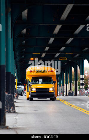 Un autobus scolaire est passé sous le pont de chemin de fer dans le Bronx, New York City, USA. Banque D'Images