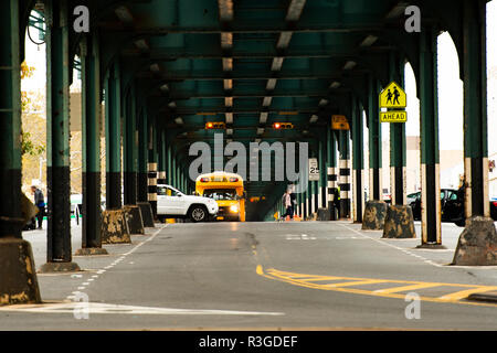 Un autobus scolaire est passé sous le pont de chemin de fer dans le Bronx, New York City, USA. Banque D'Images