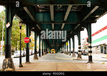 Un autobus scolaire est passé sous le pont de chemin de fer dans le Bronx, New York City, USA. Banque D'Images