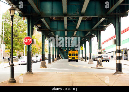 Un autobus scolaire est passé sous le pont de chemin de fer dans le Bronx, New York City, USA. Banque D'Images