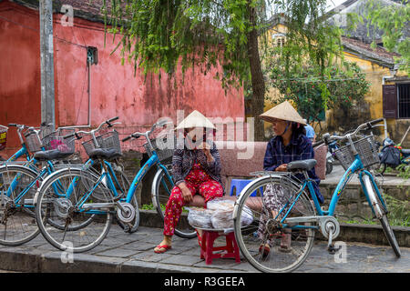 Deux femmes assises vietnamiens et de parler à Hoi An, ville ancienne en attendant que quelqu'un d'acheter leur nourriture. Banque D'Images