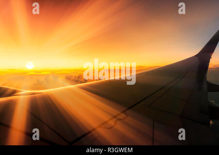 Superbe Lever du soleil sur les nuages sur avion avec plus de rayons de soleil à travers la vitre d'ailes Banque D'Images