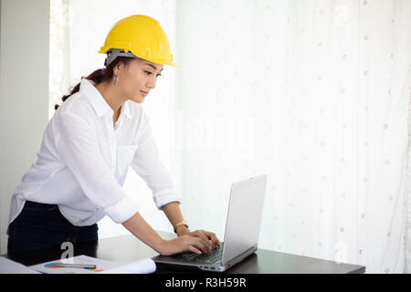 Les femmes asiatiques et l'inspection technique et de travail holding blueprints at office Banque D'Images