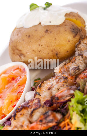 Sauté de crevettes en brochettes avec sauce à salade et pomme de terre au four Banque D'Images