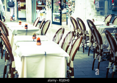 Tables en bois sur la rue étroite entre les maisons colorées typiques et petit pont à Venise,italie. Banque D'Images