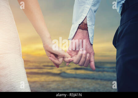 Valentin, l'amour et mariage concept. Libre d'aimer couple holding hands en marchant sur la plage au coucher du soleil. Photo pour ajouter du texte message. Backdr Banque D'Images