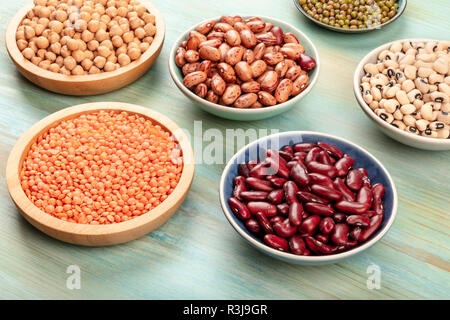 Différents types de légumineuses sur un fond bleu sarcelle. Haricots rouges, lentilles, pois chiche, soja, black-eyed peas Banque D'Images