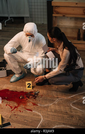 Forensic Investigator et concentarted détective féminin prise de notes et d'enquêter sur les lieux du crime ensemble Banque D'Images