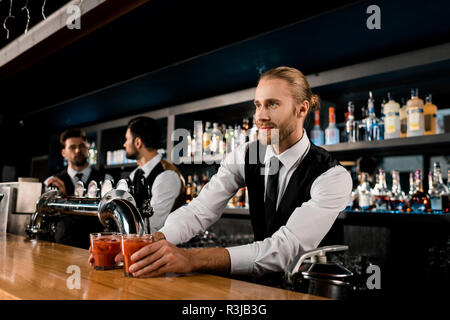 Handsome bartender sert des boissons dans des verres Banque D'Images