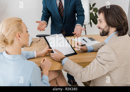 Quelques adultes contrat signature sur le presse-papiers avec un agent d'assurance in office Banque D'Images