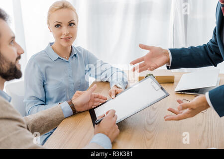 La signature de deux contrats au presse-papiers avec un agent d'assurance in office Banque D'Images