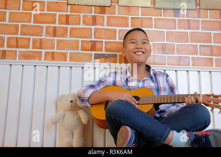 Asian kid garçon enfant à jouer de la guitare 6 cordes à la maison. Les enfants activité de loisirs Banque D'Images