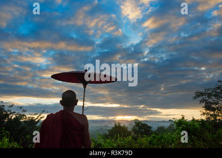 Monk avec parapluie regardant ancien temple et pagode dans la jungle au lever du soleil, Mrauk-U, l'État de Rakhine, au Myanmar Banque D'Images