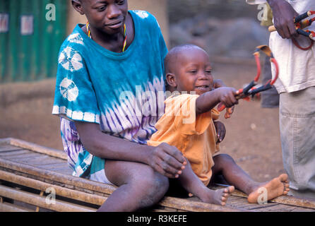 Garçon plus vieux garçon enseignent aux plus jeunes de tirer sling shot au village de la tribu d'Iwol Bedik, au Sénégal. Banque D'Images