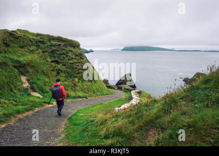 Jeune homme promenades le long chemin entouré de paysage irlandais Banque D'Images