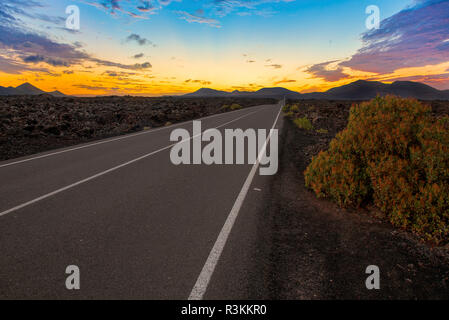 Route dans le Parc National de Timanfaya, Canaries au coucher du soleil. Banque D'Images